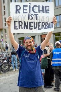 Man with sign Reiche is renewable at the demonstration of the Alliance for Renewable Energies with