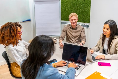 Multi ethnic colleagues using laptops and discussing during a productive meeting in a coworking