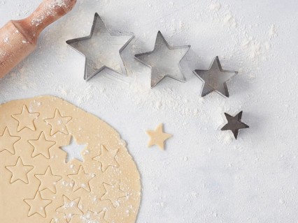 Baking at home for Christmas, dough cut with star-shaped pastry cutters of different sizes. Wooden