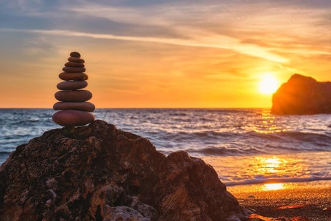 Cairn stack of stones pebbles cairn on the beach coast of the seaon sunset. Agios Ioannis beach,