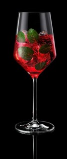 Wine glass filled with ice cube cubes and cocktail in front of a black background, mint leaves as