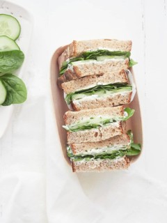Healthy vegetable sandwiches with cucumber and green spinach leaves, placed cut in halves in