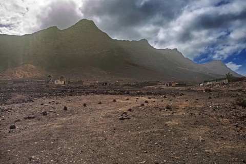 Dramatic mountain landscape with a small, lonely village (Cofete) under a cloudy sky, Pajara,