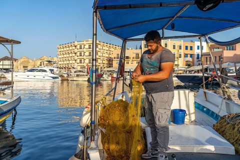 Fisherman with his net on a boat in the harbour of Chania, Crete, Greece