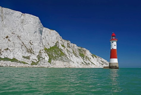 Lighthouse in front of white cliffs at the sea under blue sky, sight, Beachy Head Lighthouse,