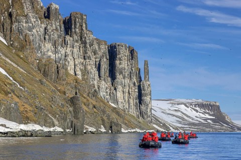 Eco-tourists in boats watch thick-billed murres, Brünnich's guillemots (Uria lomvia) nesting at