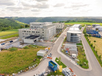 Progressive construction of a building complex along a road with a hilly landscape, construction of