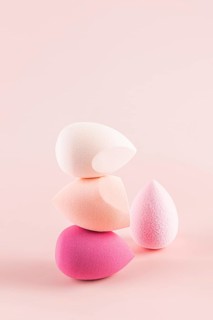 Delicately balanced stack of vibrant makeup sponges, showcasing various shapes and shades of pink