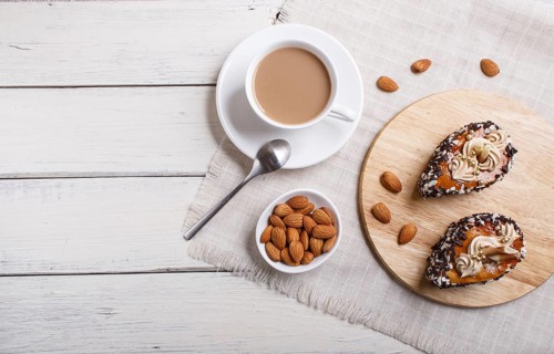 Cakes with chocolate chips and cream decorations on wooden board on white wooden background. with