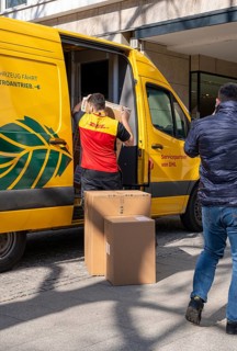 Parcel carrier unloading the delivery from a yellow DHL vehicle, Berlin, Germany