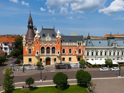 Gothic building with red and black-gray roof in the city center surrounded by urban architecture,