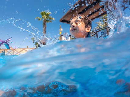 Boy splashing joyfully in a swimming pool at a vibrant water park, embracing the carefree spirit of