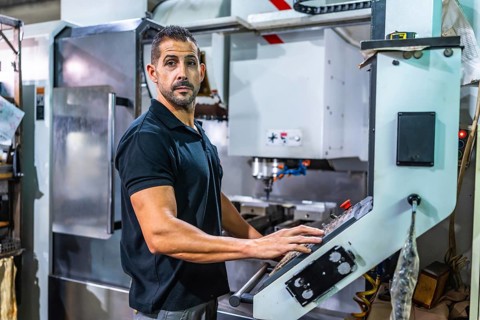 Side view of a caucasian strong manual worker using milling machine in cnc factory
