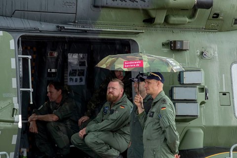 Crew of an NH 90 helicopter holding umbrellas in the rain – International Aerospace Exhibition
