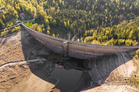 Dam in autumn landscape with bare riverbed and surrounding forest, emptied Schwarzenbach dam,