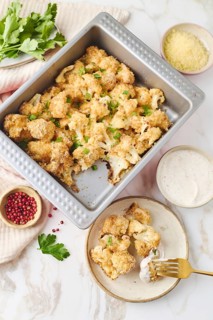 Top view of savory baked cauliflower in breadcrumbs, coated with egg and sprinkled with parsley and