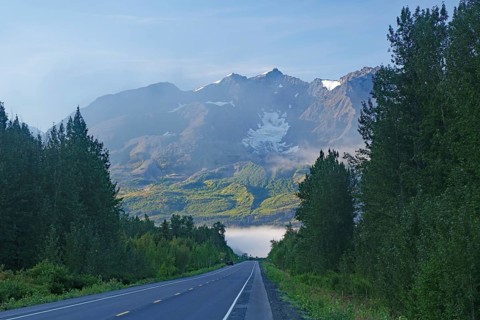 Traffic-free road leads as grades towards rugged mountains, morning fog, Richardson Highway,