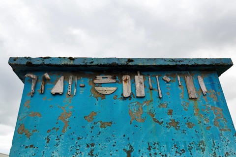 Heavily weathered blue wall, facade, corrosion, peeling paint, various pieces of wood, driftwood,