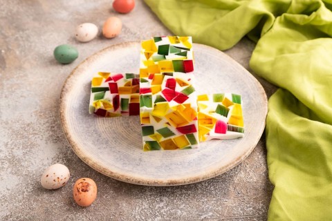 Colored Fruit and milk jelly on brown concrete background and green linen textile, side view, close