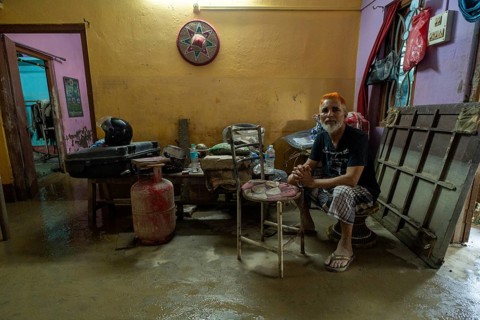 Resident sit inside his mud-filled and flood-damaged home after floodwaters receded on July 26,