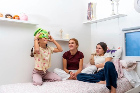 Young girls wearing pajamas enjoying a fun sleepover, one girl trying on a green novelty sleep mask
