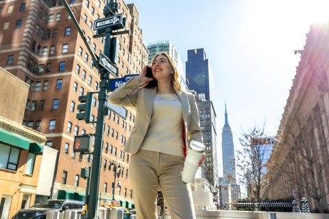 Professional businesswoman talks on her cellphone while walking confidently through bustling new