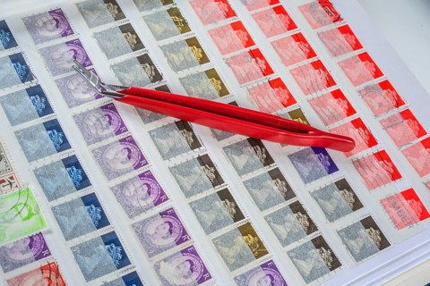 Philately, tweezers on album page with English stamps