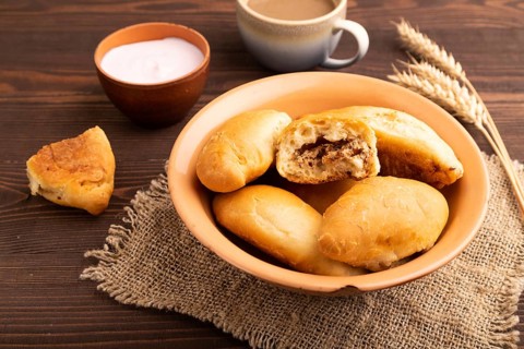 Homemade pies with jam and curd, cup of coffee, on brown wooden background with linen textile,