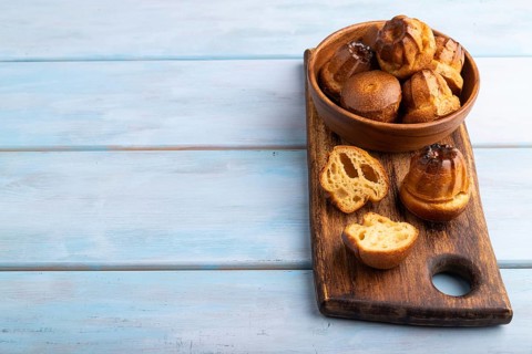 Golden caramelized Canele cookies dessert, on blue wooden background, Copy space, side view