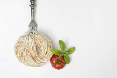 Spaghetti with fork and tomato, cutlery