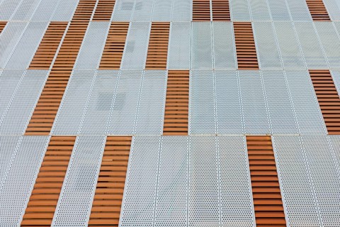 An abstract geometric pattern on a building facade showcases perforated metal panels with