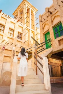 Doha Qatar Katara Cultural Village woman climbing stairs traditional wind tower architecture mud