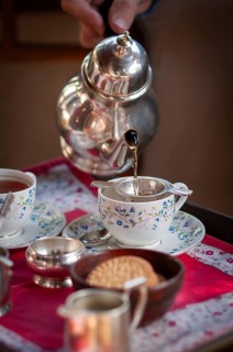 English tea is poured from an old teapot into a fine porcelain tea cup, traditional English