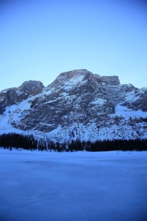 Snowy mountains, a forest in the foreground, cold and quiet with soft evening light, Pragser