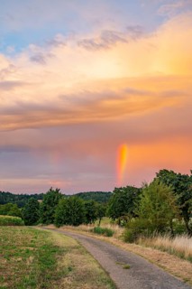 Rainbow in the sky at evening light over a walking parth in an agricultural landscape, Upper