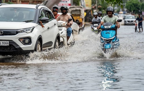Commuters passing through a waterlogged street following heavy rainfall in Guwahati, India, on 1