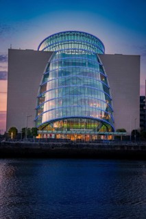 Illuminated modern building with glass façade at night, situated on the banks of a river, The
