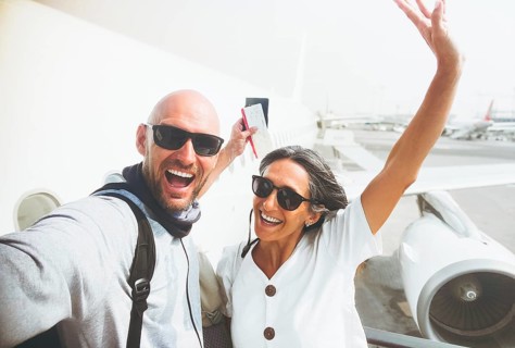 Cheerful excited caucasian couple taking selfie pose with boarding pass, passport in front of