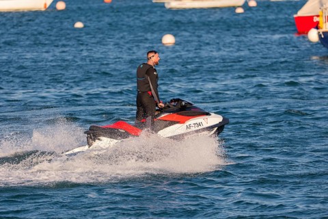 A man rides fast across the water on a jet ski, Howth Harbour, Ireland