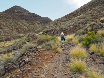 Person hiking on a rocky path through hilly landscape, La Aldea de San Nicolas, Gran Canaria, Spain