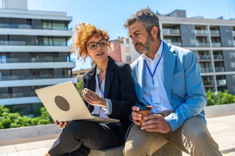 Two business professionals, a woman and a man, collaborating and discussing a project outdoors