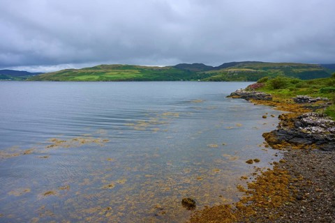 Lake with calm cloudy sky and green hills in the background, Portnalong, Isle of Skye, Scotland,