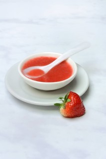 Strawberry sauce in small bowls and strawberries, strawberry coulis
