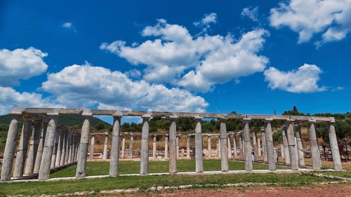 Ancient structure of columns in a meadow under a cloudy sky, ancient site, archaeological site,