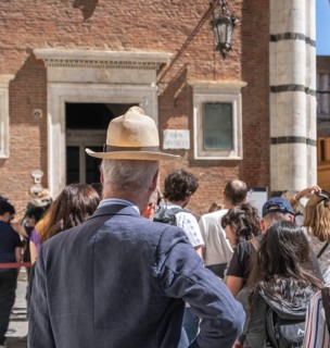 Tourist with too small head covering, summer hat with brim, Siena, Tuscany, Italy