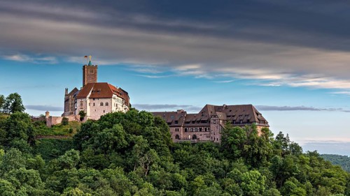 Historic castle on a wooded hill under a dramatic sky, The Wartburg near Eisenach in Thuringia