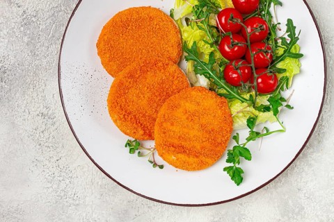 Crispy fried fish cutlets, fish burgers, on a white plate, with fresh lettuce leaves, arugula and