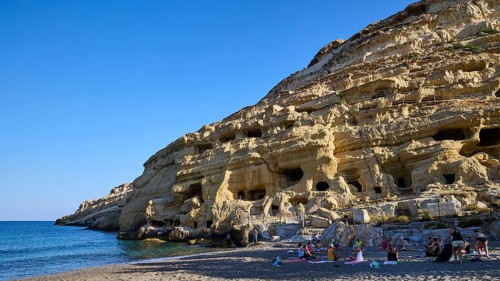 Neolithic caves, former hippie paradise, woman yoga group, people on the beach in front of
