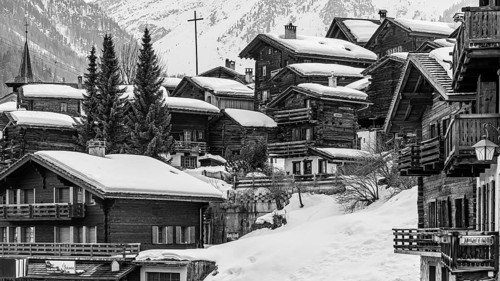Snow-covered old farmhouses, large wooden cross, black and white photo, historic town center,