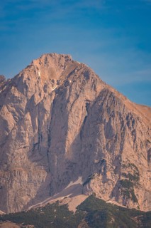 High mountain peak under clear blue sky with steep rock face, Hahnenkamm, Kitzbühel, Austria